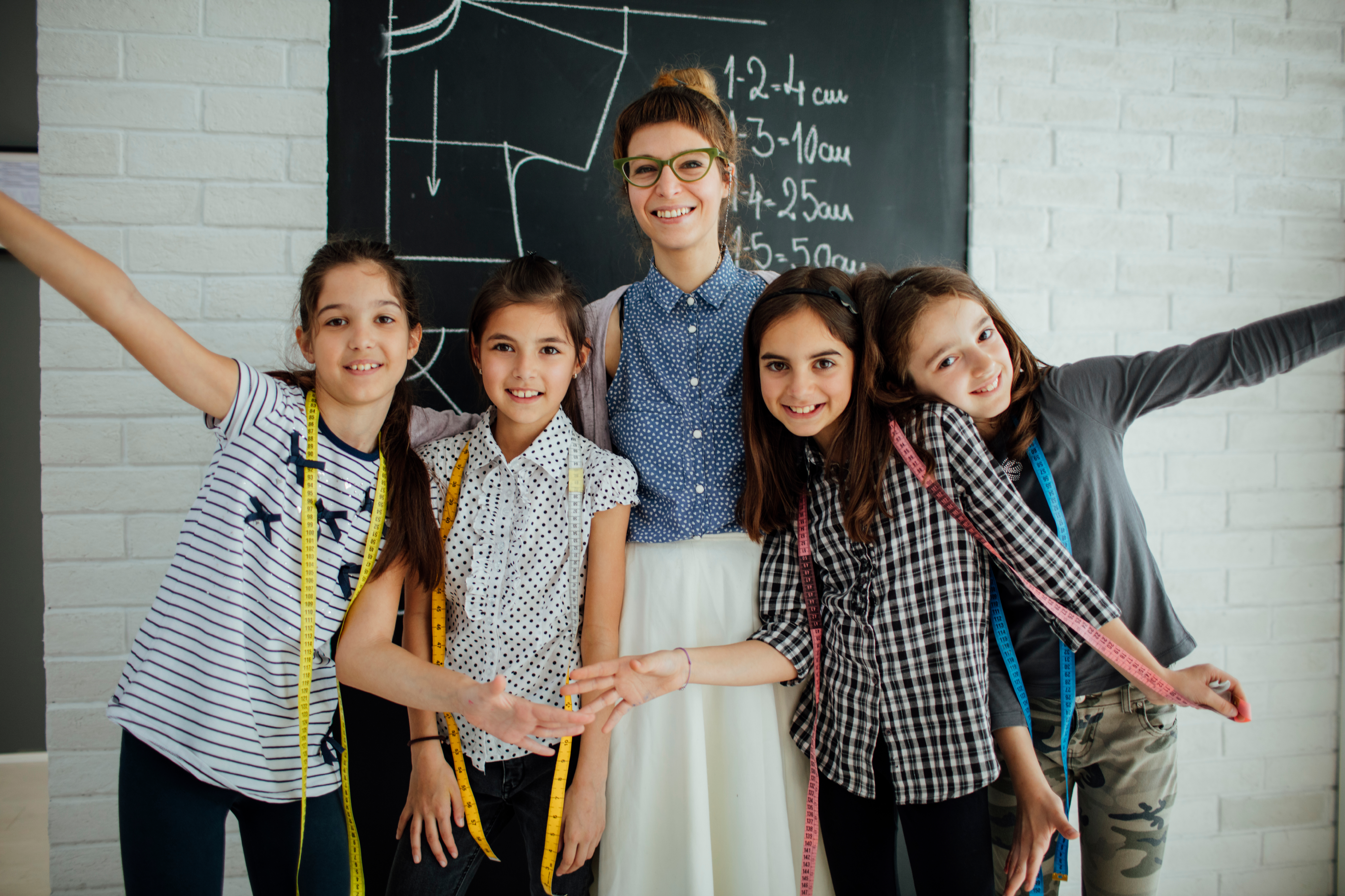 Kvinna står tillsammans med fyra glada barn framför en tavla