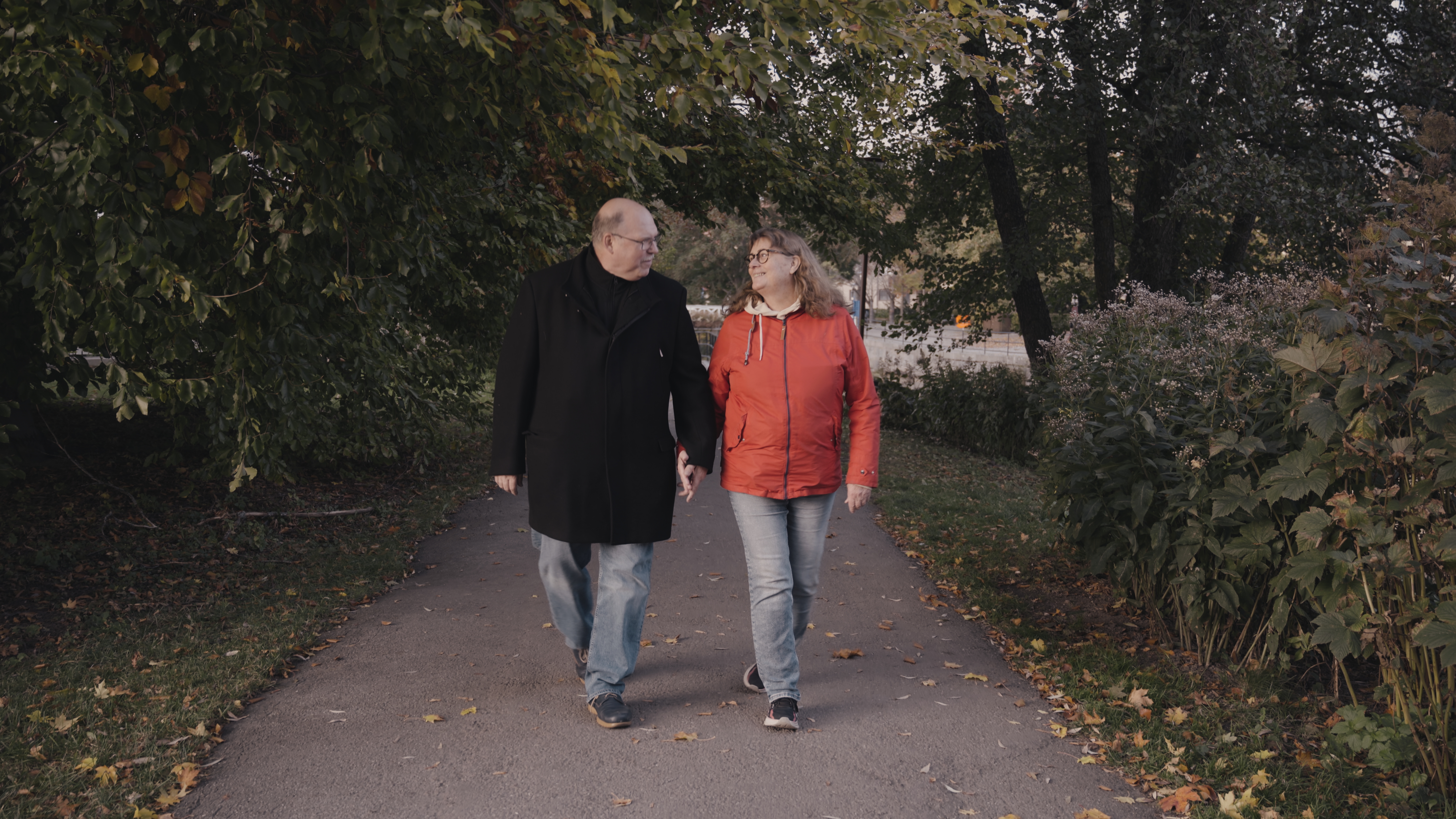 Ett pensionärspar på promenad håller varandra i handen