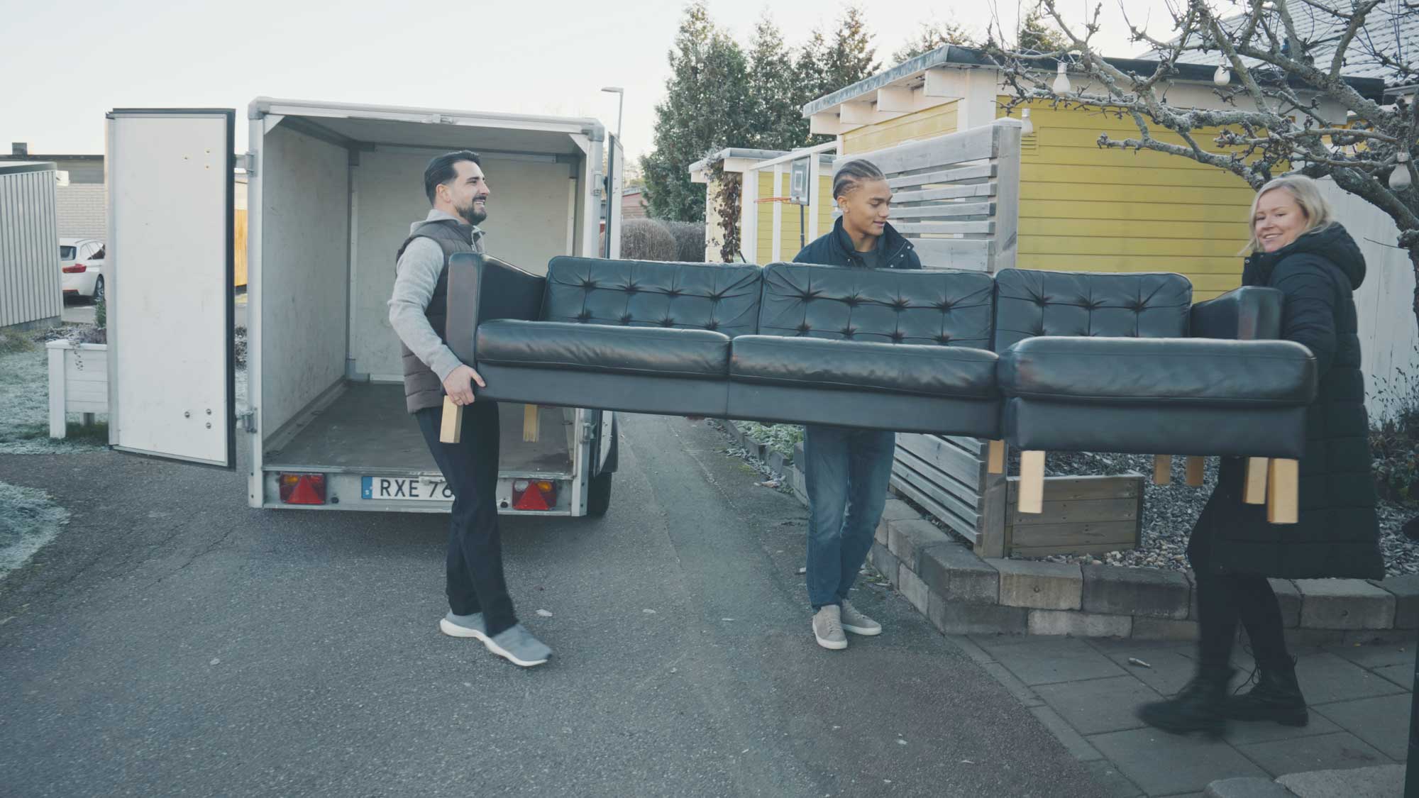 tre personer bär en soffa