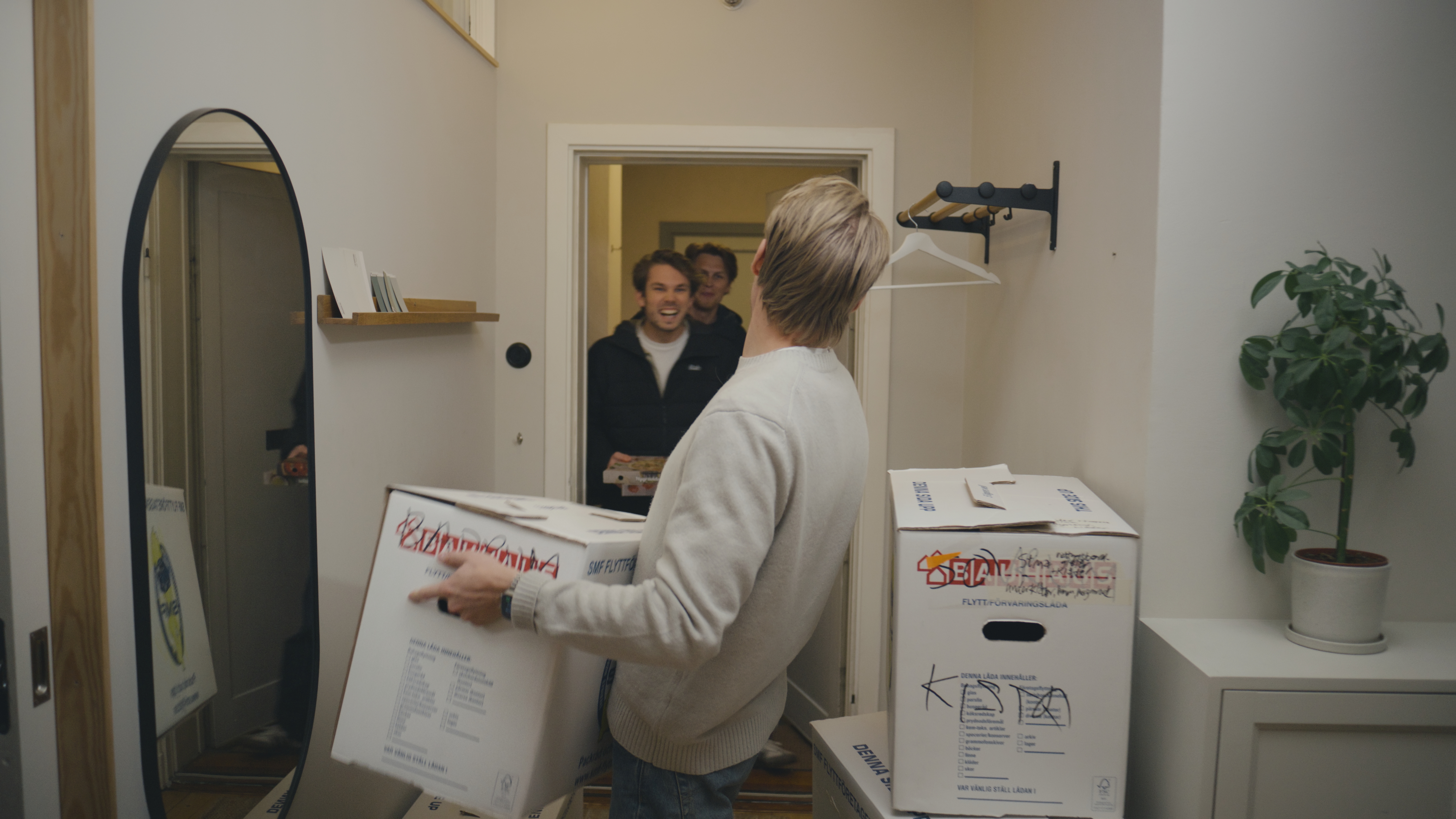 ung man bär flyttkartonger i en hall