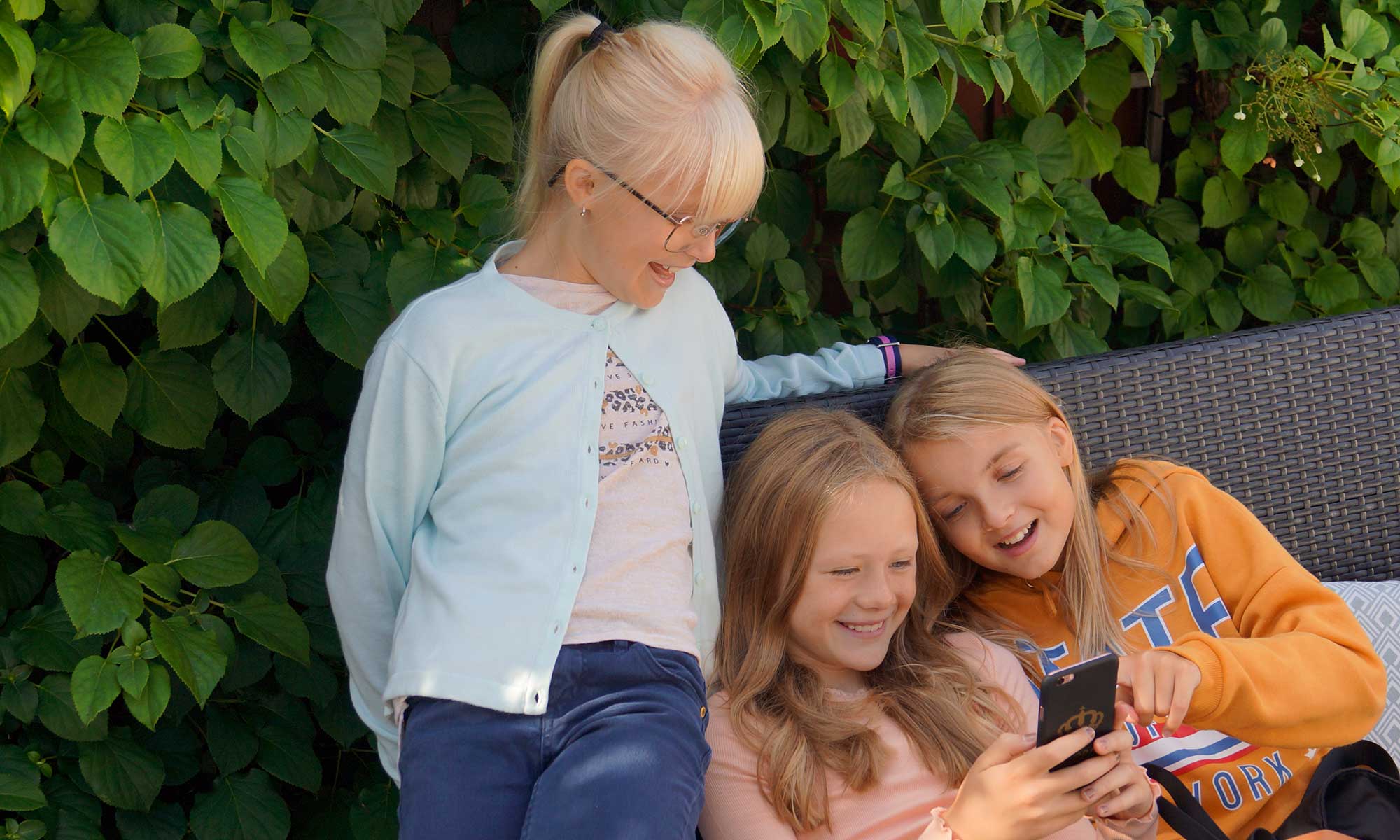 barn utomhus i en soffa tittar på en mobilskärm