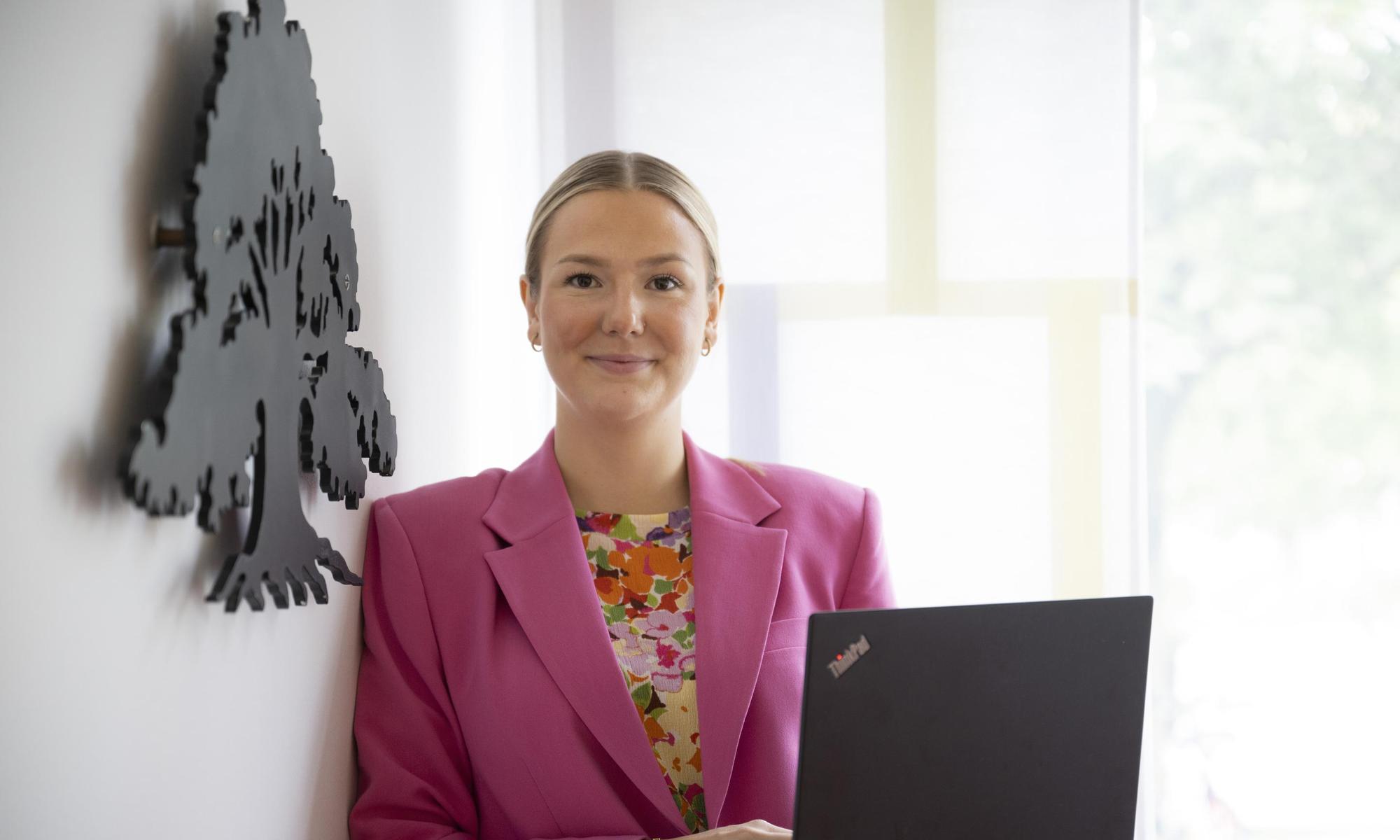 women in a pink jacket holding a computor