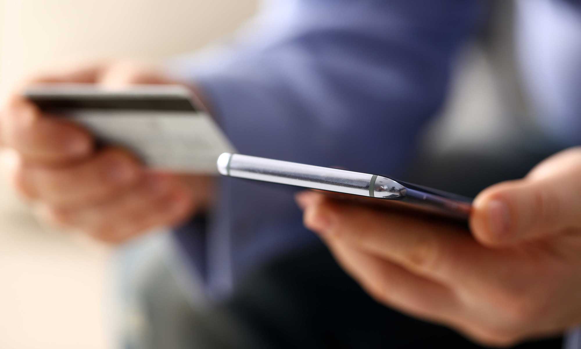 a person holding a creditcard and a smartphone in his hands