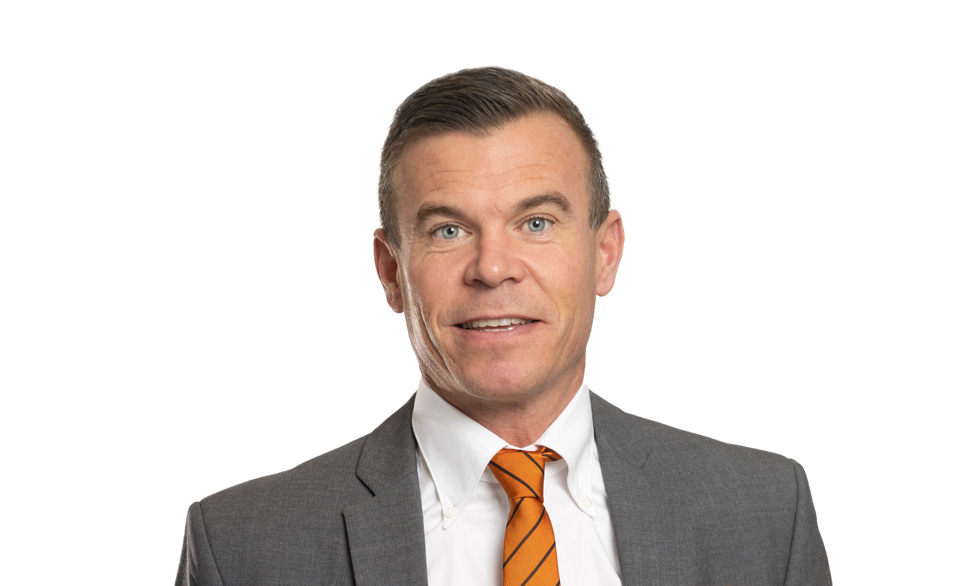 man i grå kostym, vit skjorta och orange slips