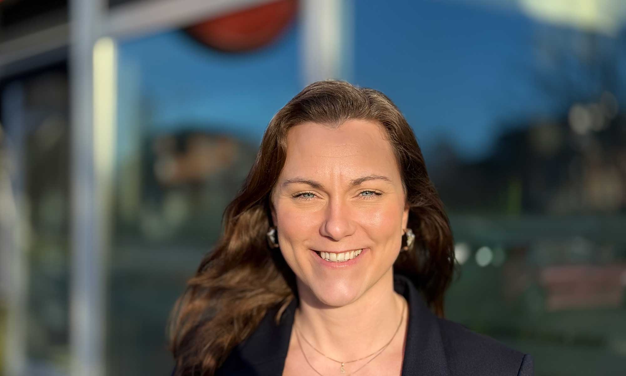 a women standing outside is smiling into the camera