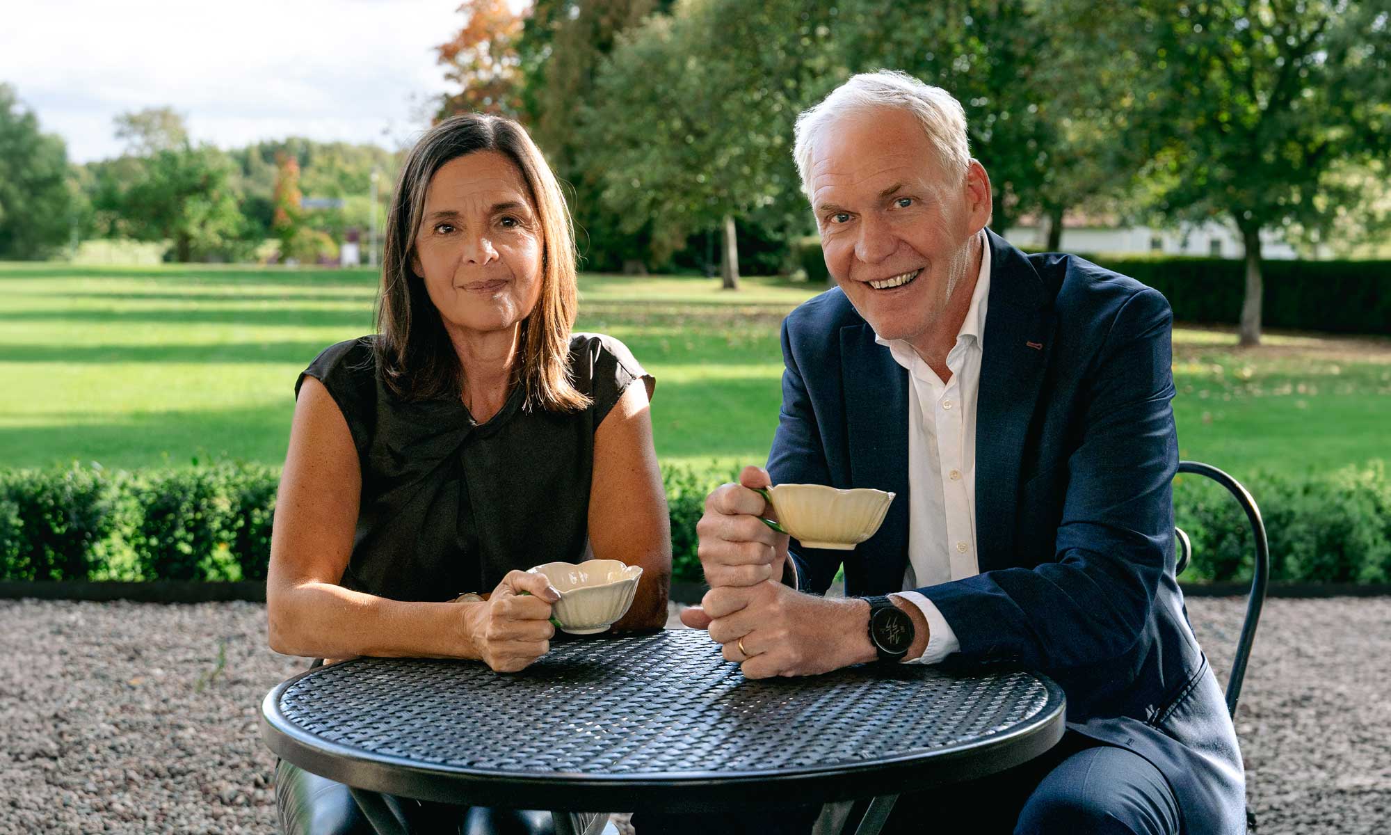 Kvinna och man sitter vid ett kafé-bord med utsikt över parken 
