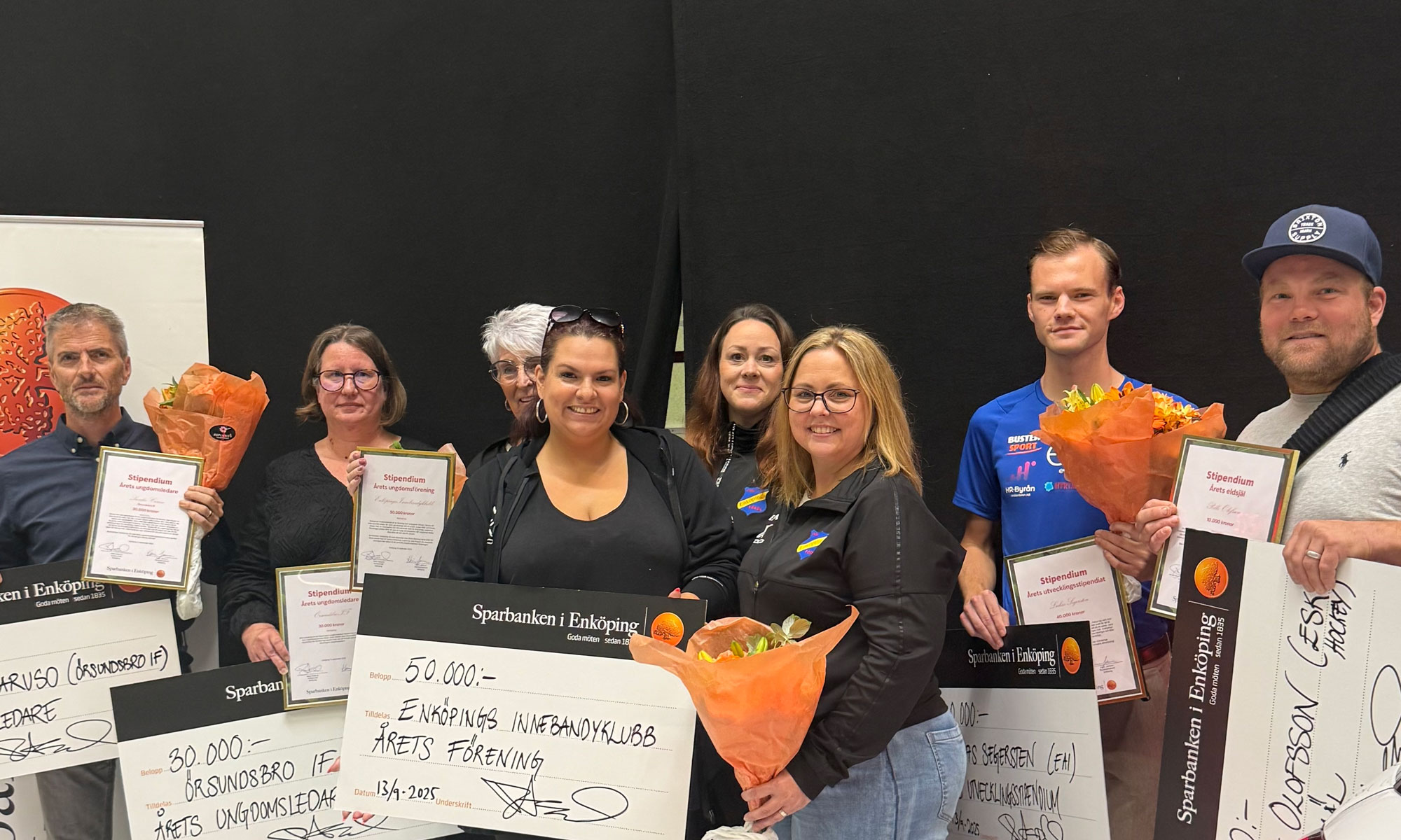 8 personer hållandes diplom och blombuketter