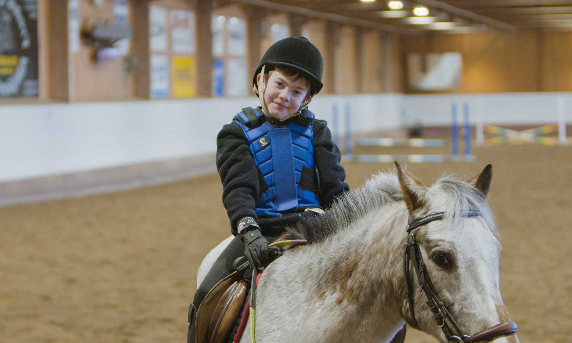 Ett barn sitter på en vit häst